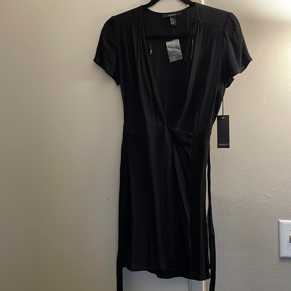 Never worn Forever 21 wrap black dress, tag and extra button attached. Size S
